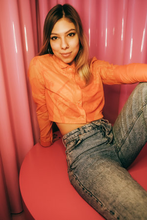 Young stylish attractive caucasian woman posing in a room with pink walls.の写真素材