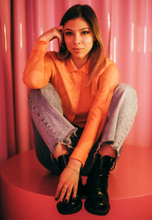 Young stylish attractive caucasian woman posing in a room with pink walls.の写真素材