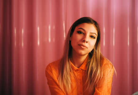 Young stylish attractive caucasian woman posing in a room with pink walls.の写真素材