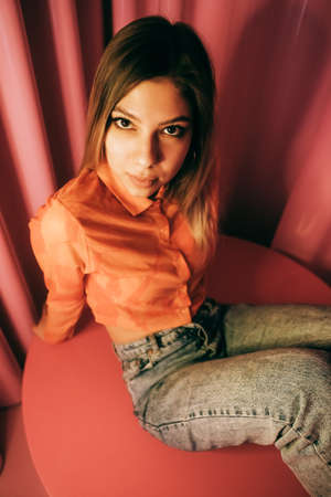 Young stylish attractive caucasian woman posing in a room with pink walls.の写真素材