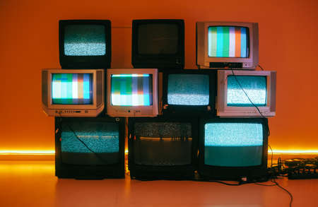 Old vintage tvs on a floor in a room with colored neon light.の写真素材