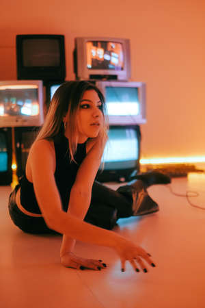 Young attractive caucasian woman posing on floor near stand with old vintage tvs.の写真素材