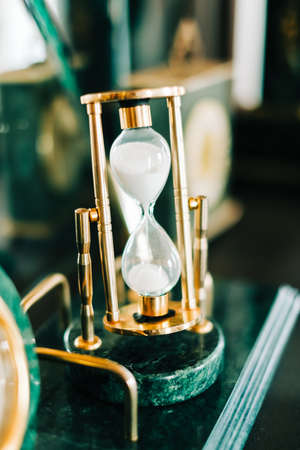 Vintage golden hourglass on the table, closeup.の写真素材