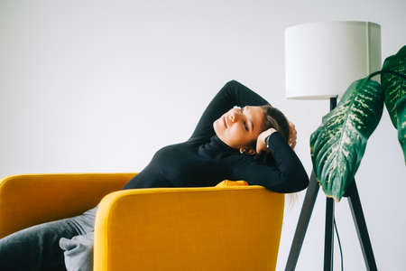 Portrait of young attractive stylish caucasian woman relaxing on armchair.の写真素材