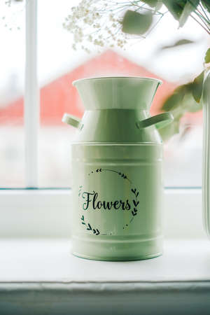 Green metal vase for flowers on a windowsill at home.の写真素材