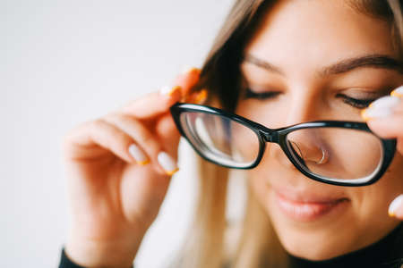 Young caucasian woman trying on glasses in opticians store, close up.