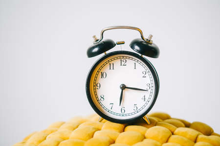 Black alarm clock on a yellow chair, close up.の写真素材
