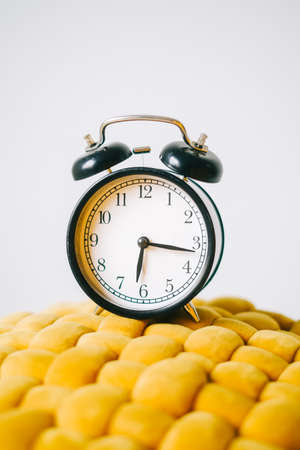 Black alarm clock on a yellow chair, close up.の写真素材
