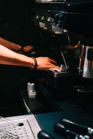 Barista man cleaning coffee machine after working day in asian cafe.の写真素材