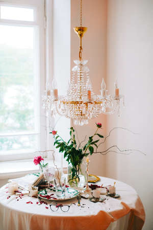Interior of bright living room with chandelier and table with flowers.の写真素材