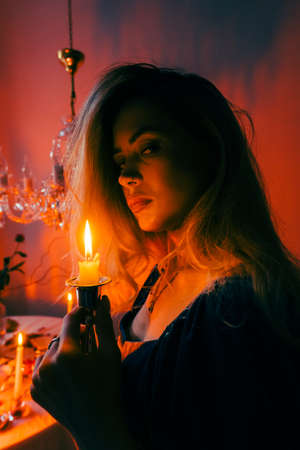 Portrait of attractive caucasian woman with candlestick in the dark, vintage elegant interior.の写真素材
