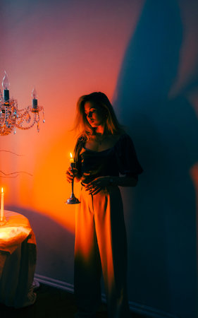 Portrait of attractive caucasian woman with candlestick in the dark, vintage elegant interior.の写真素材