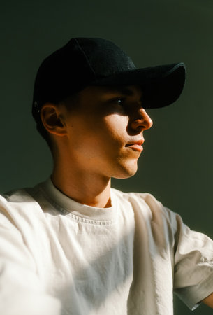Portrait of stylish handsome caucasian man fashion model in t shirt and cap, studio shot.の写真素材