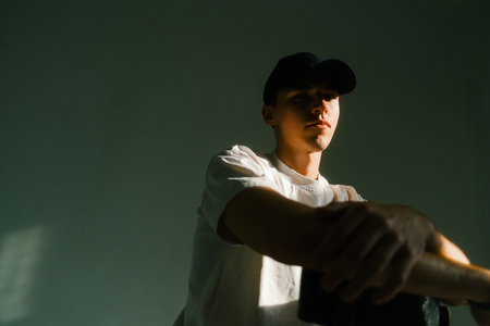 Portrait of stylish handsome caucasian man fashion model in t shirt and cap, studio shot.の写真素材
