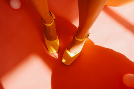 Perfect tan woman feet in yellow shoes on pink background.の写真素材