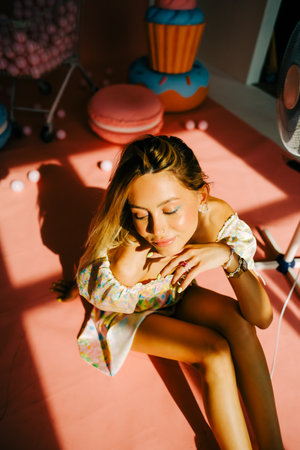 Portrait of attractive caucasian woman fashion model with blond hair, on pink background with figures of sweets and candies.の写真素材