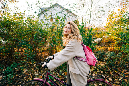 Young attractive caucasian woman ride on bicycle in the park on warm day in the fall.の写真素材