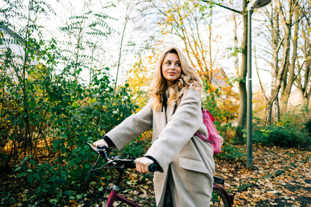 Young attractive caucasian woman ride on bicycle in the park on warm day in the fall.の写真素材