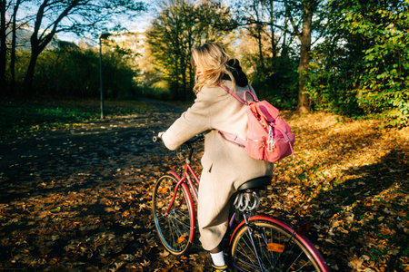 Young attractive caucasian woman ride on bicycle in the park on warm day in the fall.の写真素材