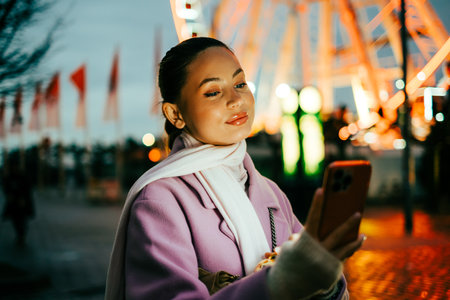 Portrait of attractive caucasian woman using mobile phone in the city square on the evening.の写真素材