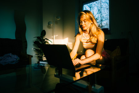 Portrait of young caucasian woman college student studying with laptop, distantly preparing for test exam, writing essay doing homework at home.の写真素材