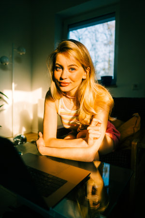 Portrait of young caucasian woman college student studying with laptop, distantly preparing for test exam, writing essay doing homework at home.の写真素材