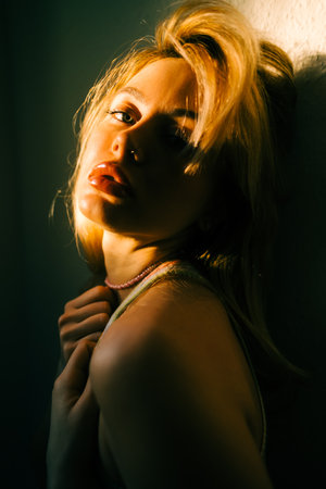 Portrait of attractive caucasian woman with blonde hair posing in sunset light indoor.の写真素材