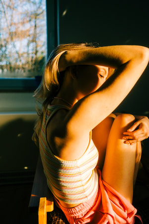 Portrait of attractive caucasian woman with blonde hair posing in sunset light indoor.の写真素材