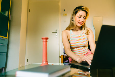 Portrait of young caucasian woman college student studying with laptop, distantly preparing for test exam, writing essay doing homework at home.の写真素材