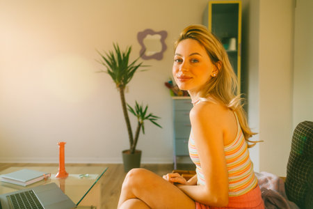 Portrait of attractive caucasian young woman in bright living room at home with sunset light.の写真素材