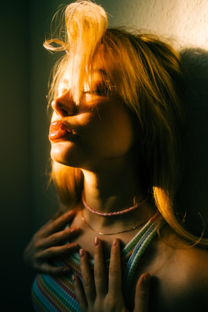 Portrait of attractive caucasian woman with blonde hair posing in sunset light indoor.の写真素材