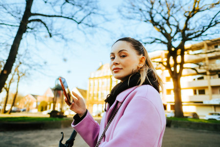 Young attractive caucasian woman using mobile phone, ride on bicycle in the city street.の写真素材