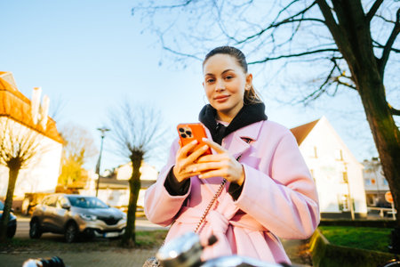 Young attractive caucasian woman using mobile phone, ride on bicycle in the city street.の写真素材
