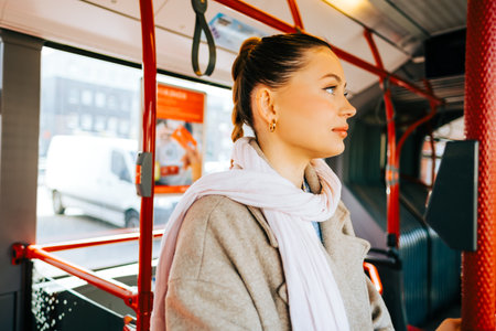 An attractive caucasian woman riding in a bus in the sunny day. Young beautiful woman using public transportation.の写真素材