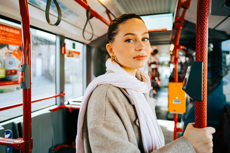An attractive caucasian woman riding in a bus in the sunny day. Young beautiful woman using public transportation.の写真素材