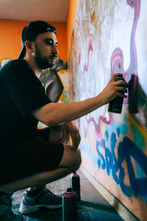 Young caucasian man graffiti artist drawing on a wall.の写真素材