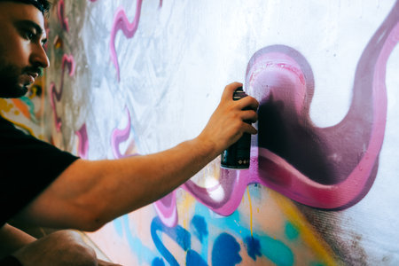 Young caucasian man graffiti artist drawing on a wall.の写真素材
