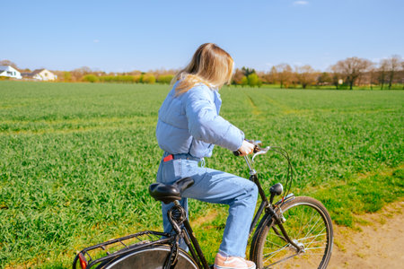 Young attractive caucasian woman ride on bicycle in countryside in sunny spring day.の写真素材