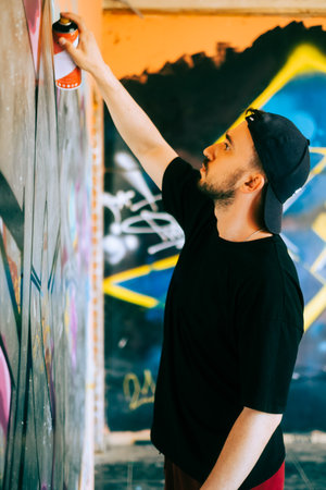 Young caucasian man graffiti artist drawing on a wall.の写真素材