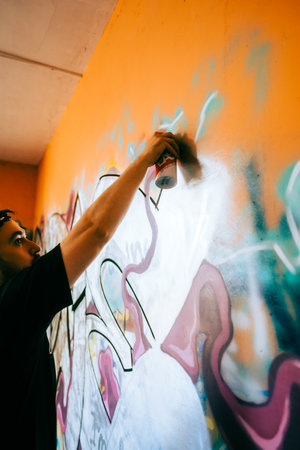 Young caucasian man graffiti artist drawing on a wall.の写真素材