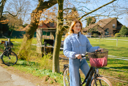 Young attractive caucasian woman ride on bicycle in countryside in sunny spring day.の写真素材
