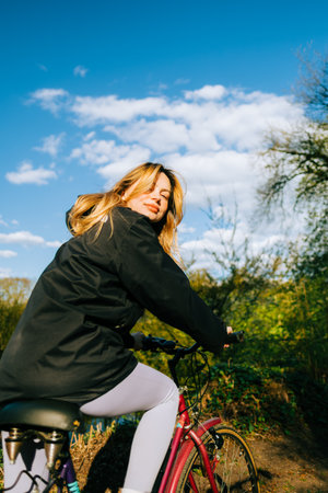Portrait of young attractive woman riding on bicycle in the park in springtime.の写真素材