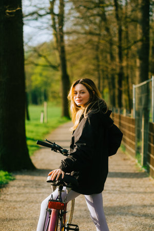 Portrait of young attractive woman riding on bicycle in the park in springtime.の写真素材
