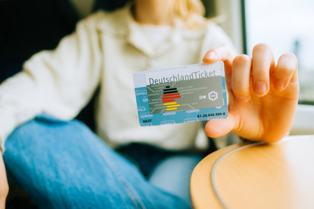 Deutschland Ticket in hands, woman holding new German subscription travel card.のeditorial素材