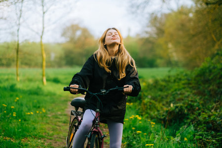 Portrait of young attractive woman riding on bicycle in the park in springtime.の写真素材