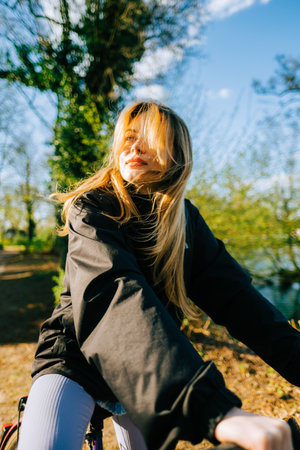 Portrait of young attractive woman riding on bicycle in the park in springtime.の写真素材