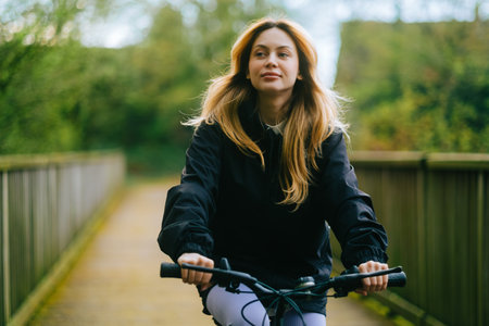 Portrait of young attractive woman riding on bicycle in the park in springtime.の写真素材