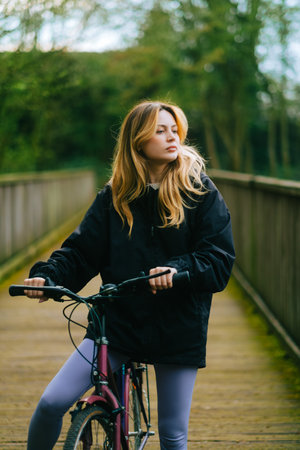 Portrait of young attractive woman riding on bicycle in the park in springtime.の写真素材