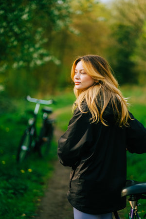 Portrait of young attractive woman riding on bicycle in the park in springtime.の写真素材