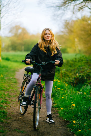 Portrait of young attractive woman riding on bicycle in the park in springtime.の写真素材